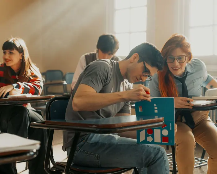 Dois estudantes estudando juntos numa sala de aula iluminada